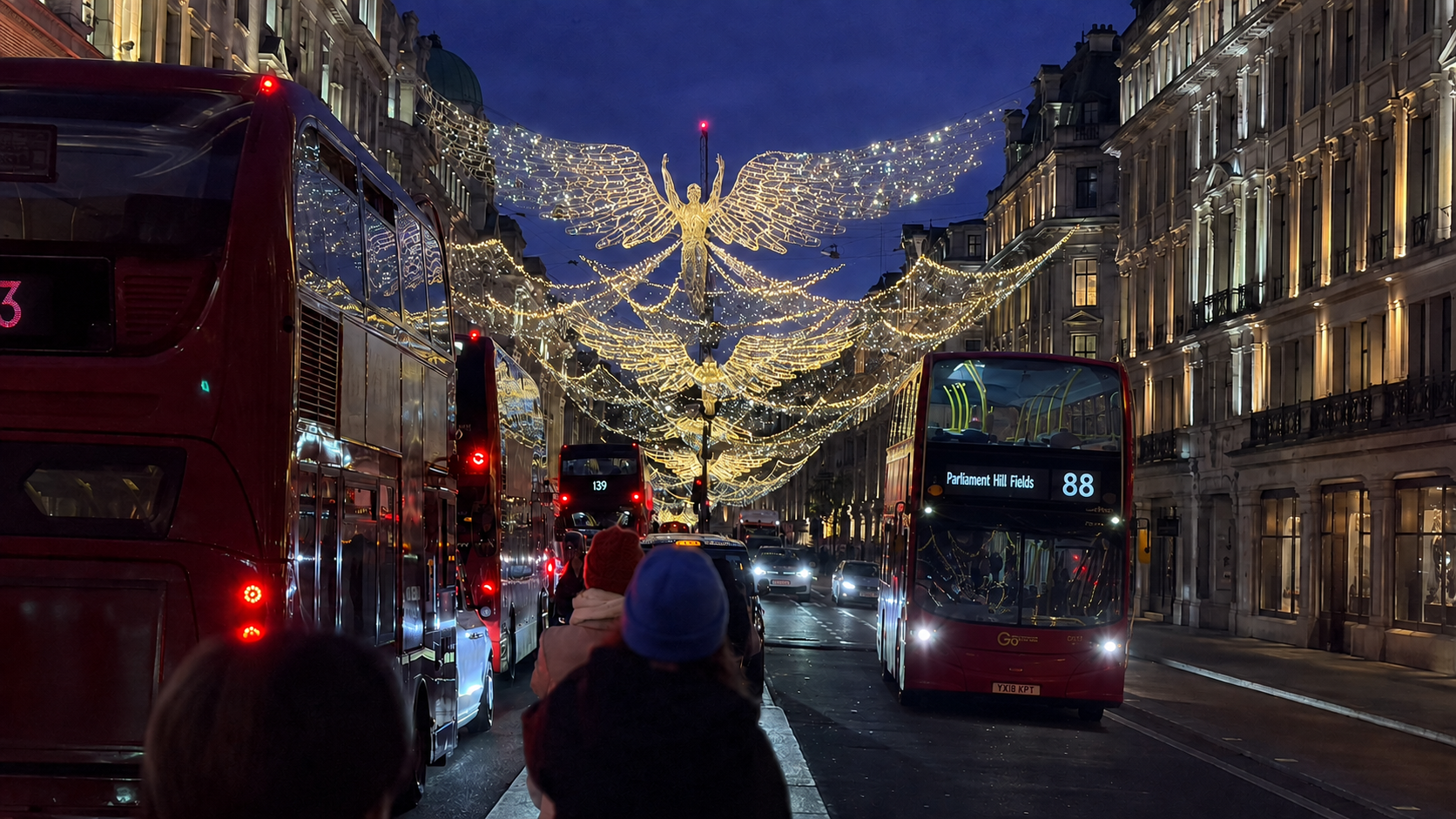Night buses beneath angel-shaped lights on a busy city street